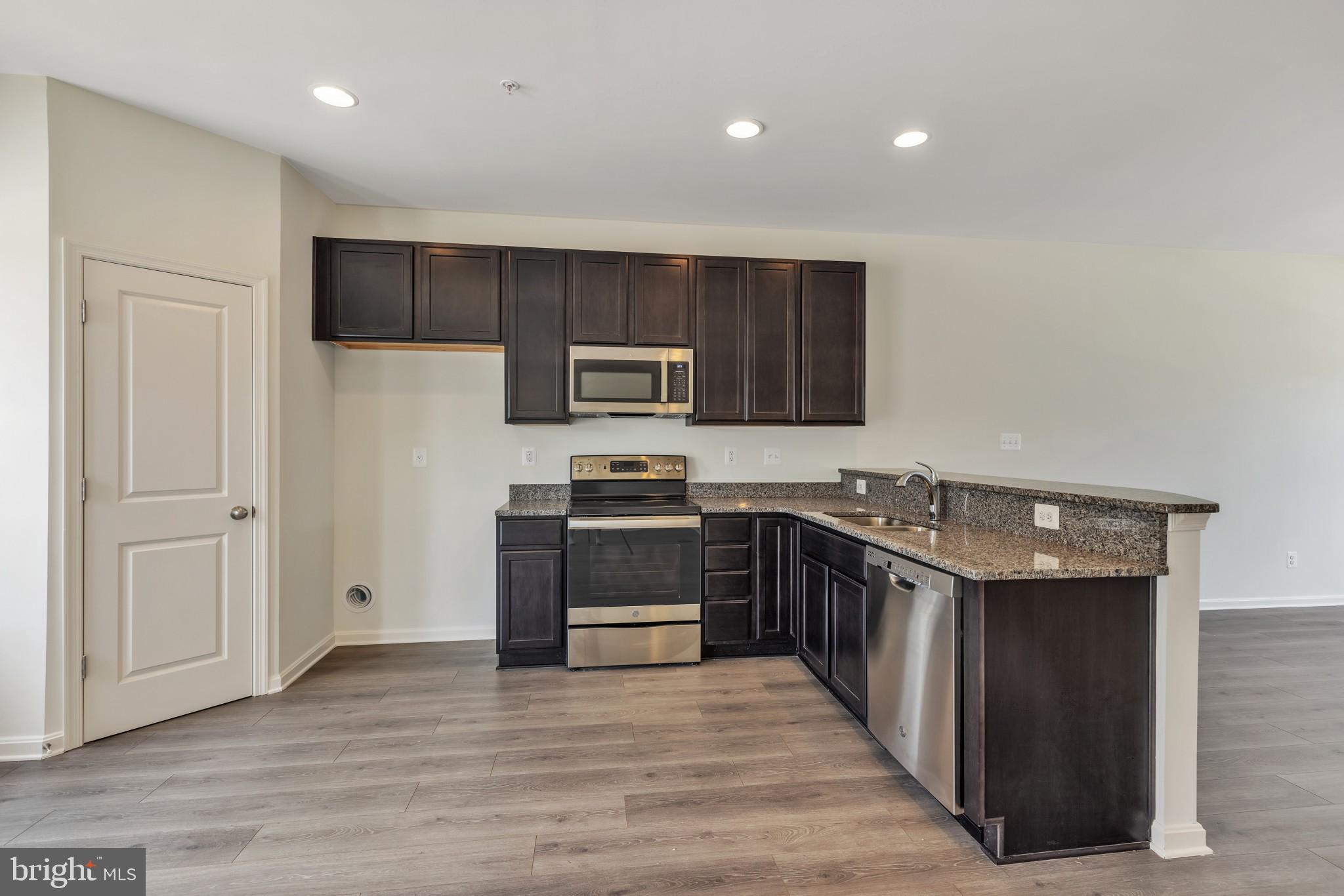 821 Magnolia Ridge Court Joppa, MD 21085 - Photo 14 of 33 a kitchen with stainless steel appliances a stove top oven a sink a refrigerator white cabinets and wooden floor