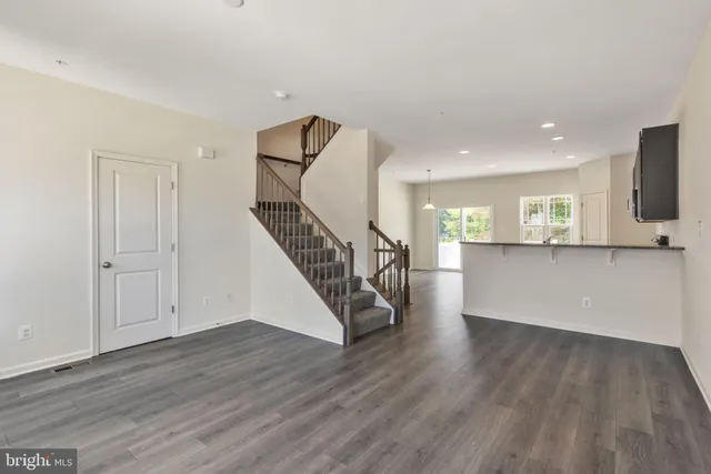 a view of a kitchen and an empty room with wooden floor