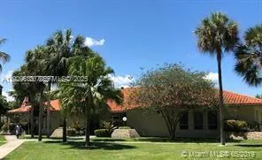 a view of a white house with a big yard and potted plants