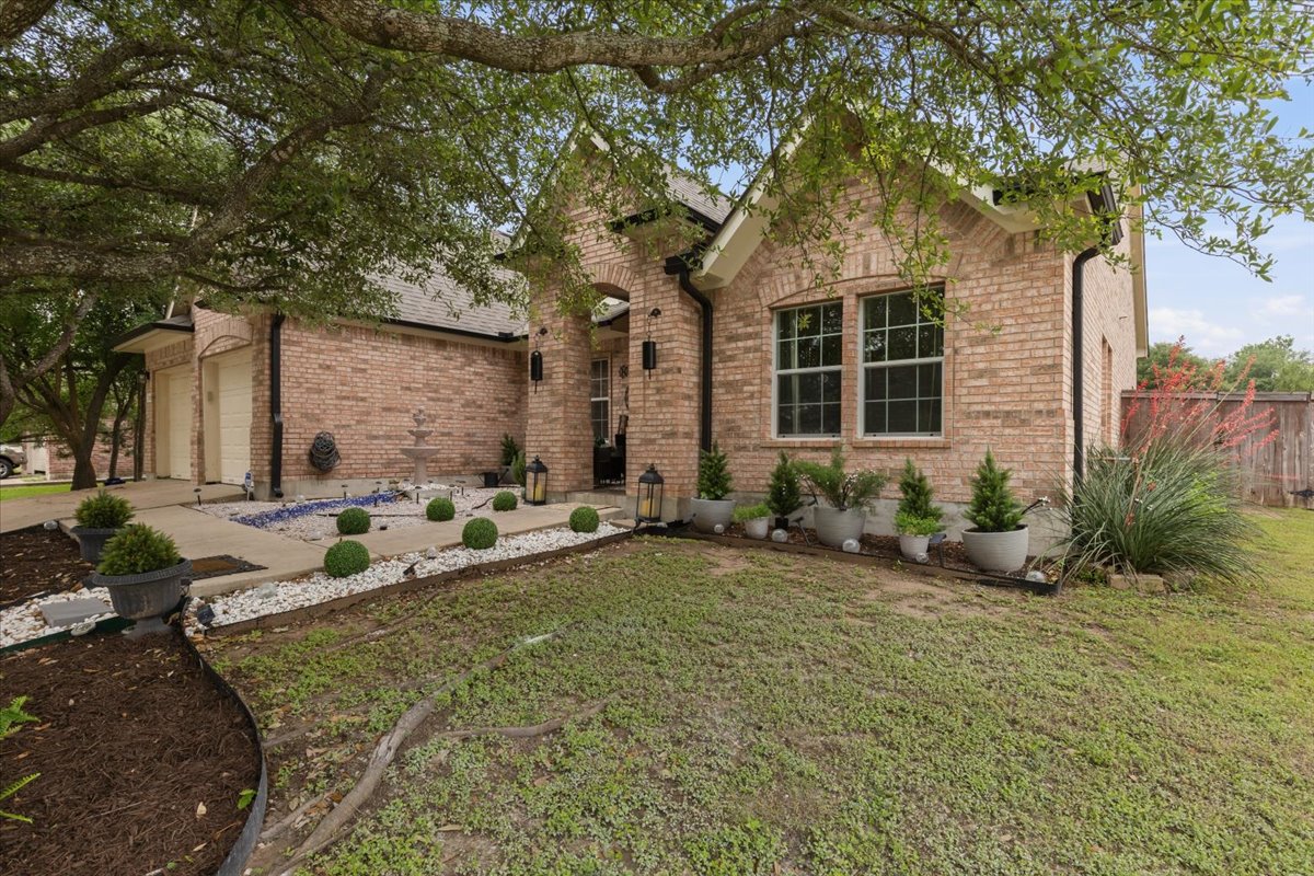 2501 Aspen Meadow Road Leander, TX 78641 - Photo 3 of 30 Brick exterior with multiple gables, a two-car garage, and established tree coverage
