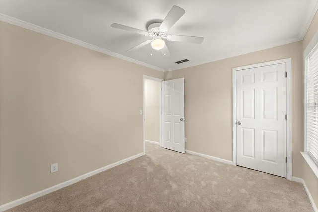 an empty room with windows and ceiling fan