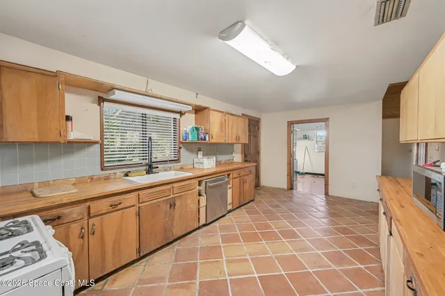 a large white kitchen with cabinets a sink a window and a potted plant