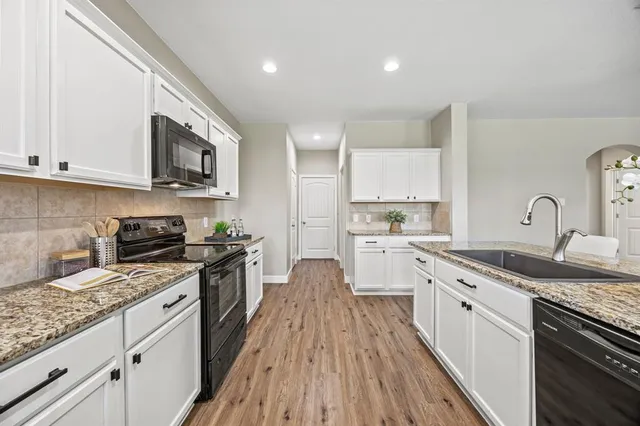 a large kitchen with a stove top oven a sink a microwave and wooden floor