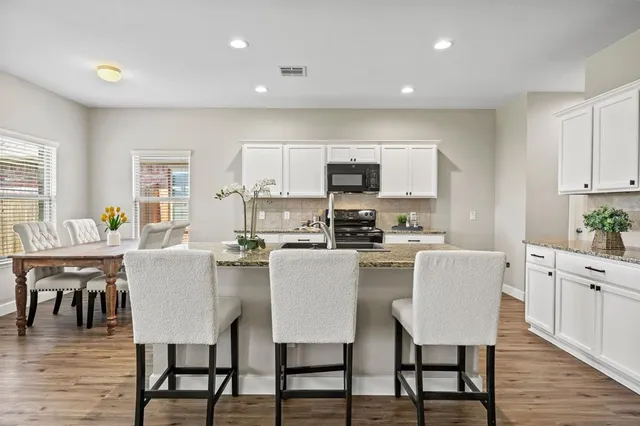 a kitchen with kitchen island a dining table chairs and white cabinets