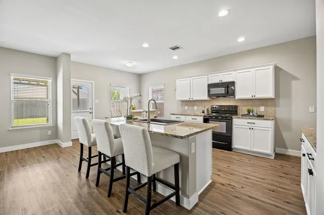 a kitchen with a table chairs a sink dishwasher refrigerator and cabinets