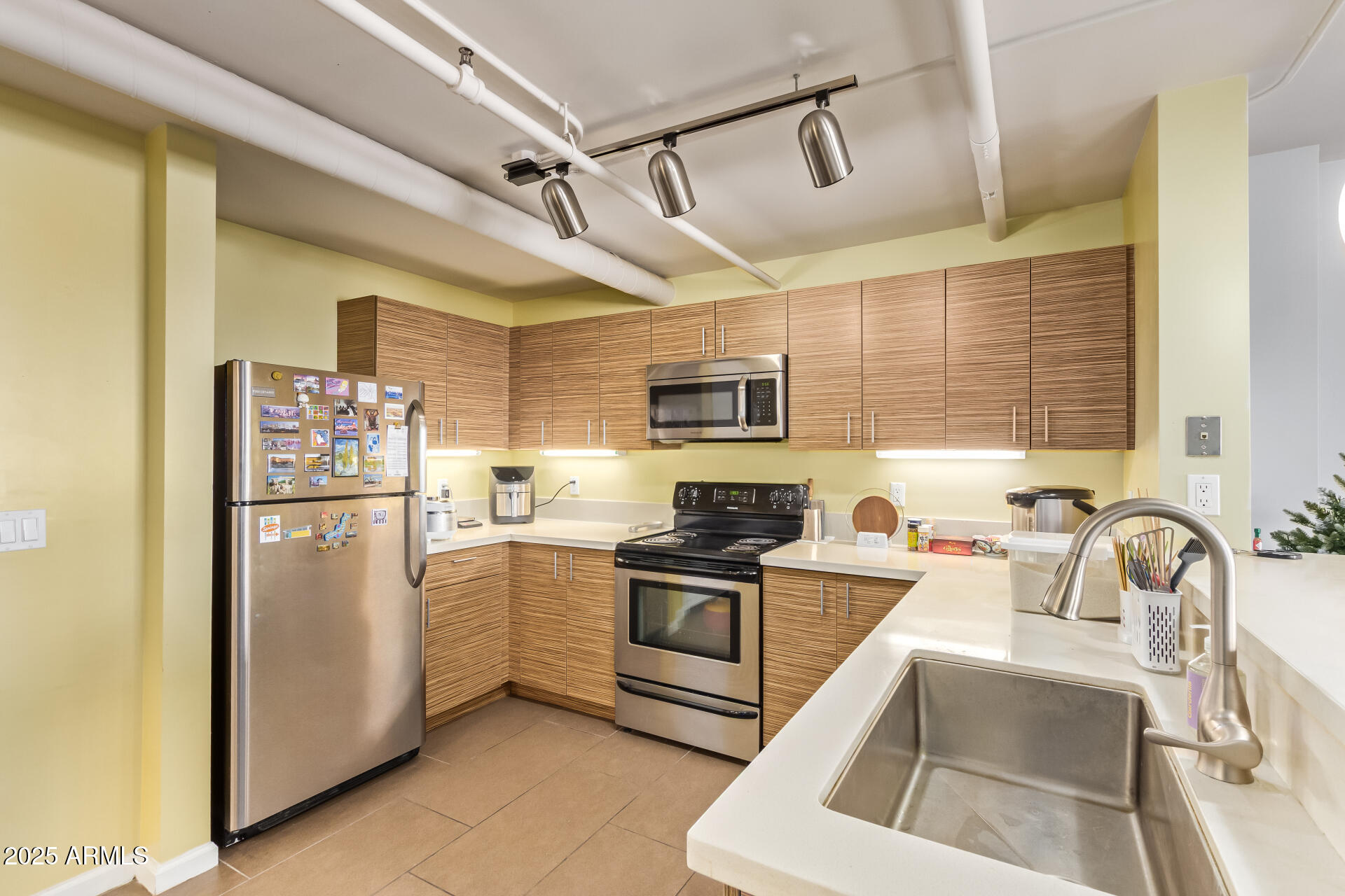 535 West Thomas Road, Unit 313 Phoenix, AZ 85013 - Photo 21 of 31 a kitchen with stainless steel appliances granite countertop a refrigerator a sink a stove and white cabinets with wooden floor