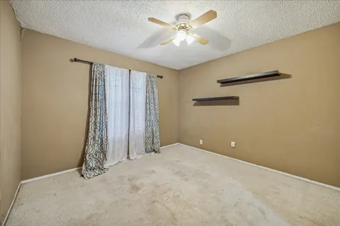 an empty room with a ceiling fan and a window