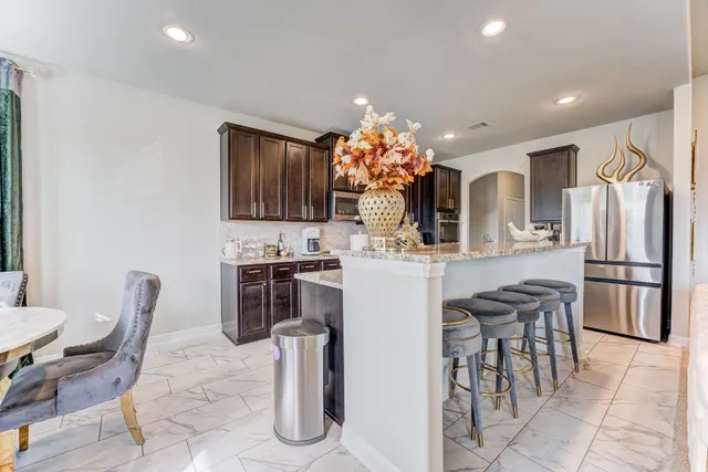 a kitchen with refrigerator and chairs