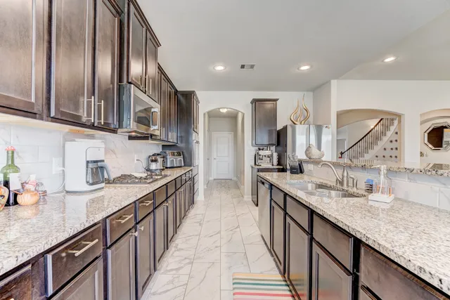 a kitchen with stainless steel appliances granite countertop a sink a stove and a wooden cabinets