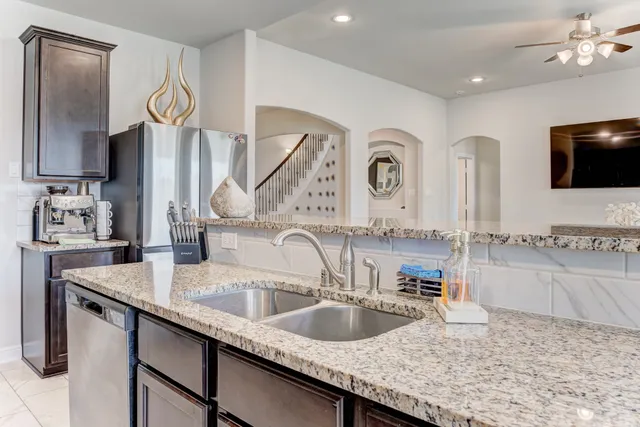a very nice looking kitchen with granite countertop a sink a stove and a wooden floor