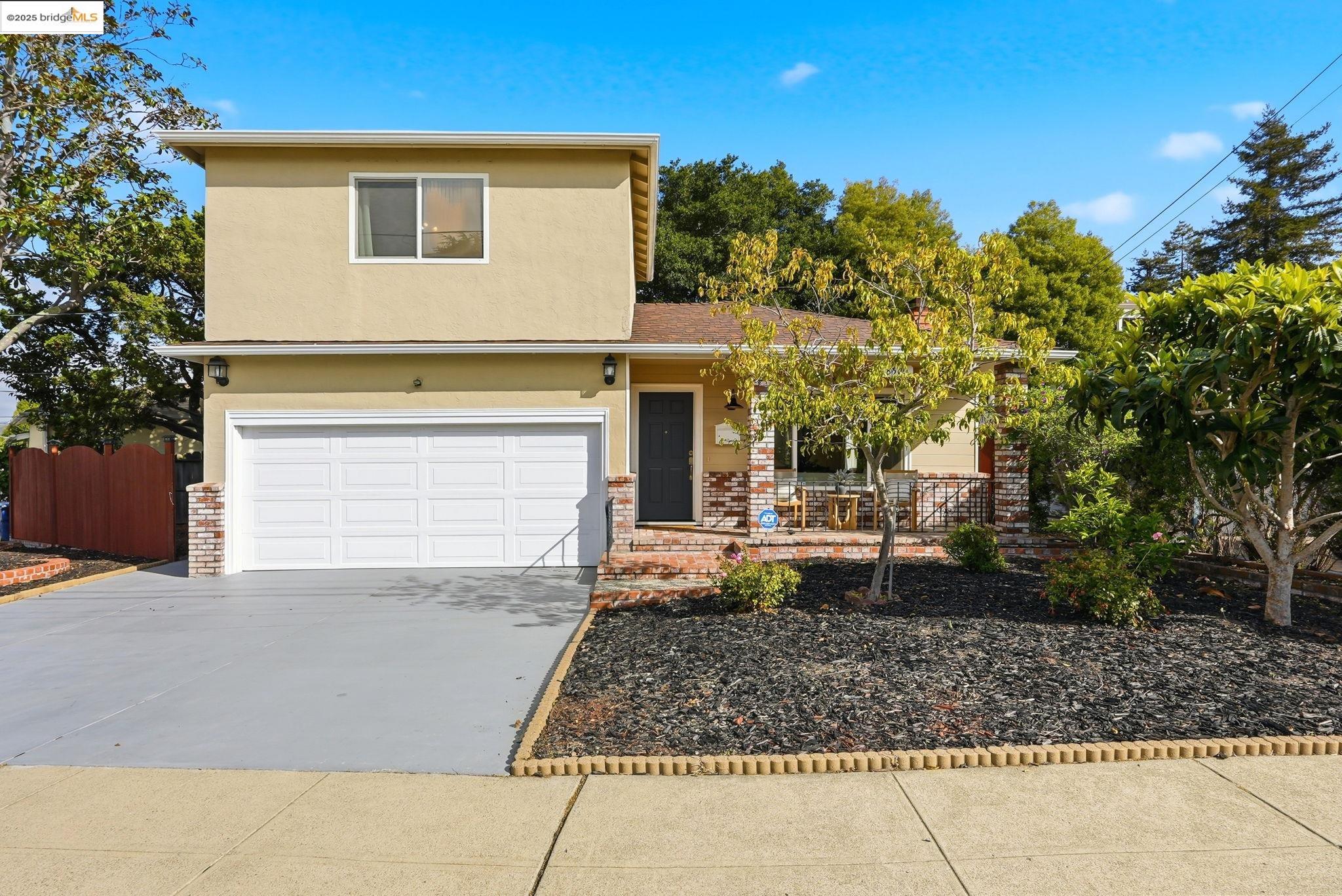 Traditional-style house featuring a porch, driveway, stucco siding, and an attached garage
