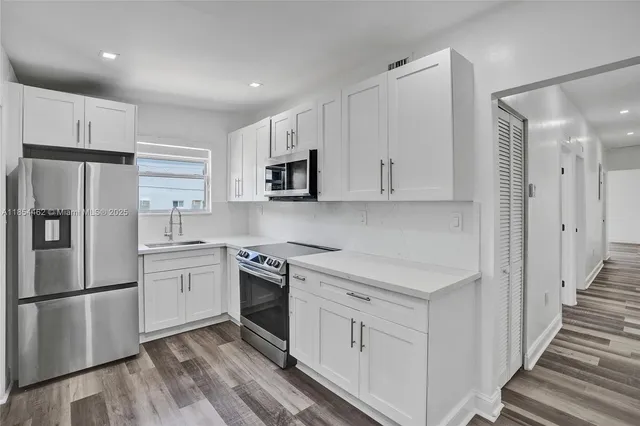 a kitchen with white cabinets stainless steel appliances and a refrigerator
