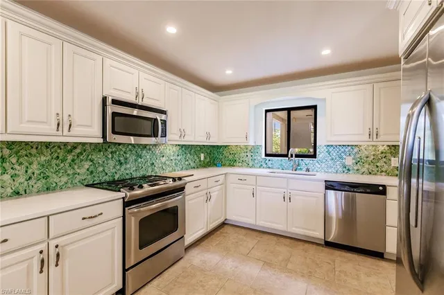 a kitchen with granite countertop white cabinets and stainless steel appliances