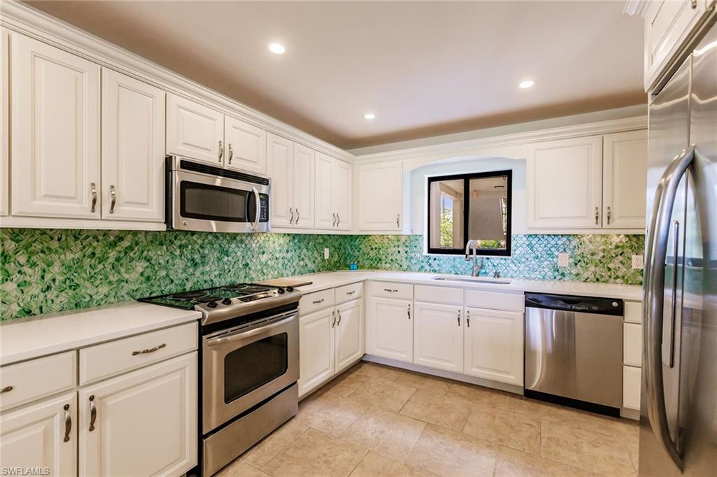 22 Cypress View Drive, Unit B22 Naples, FL 34113 - Photo 15 of 39 a kitchen with granite countertop white cabinets and stainless steel appliances