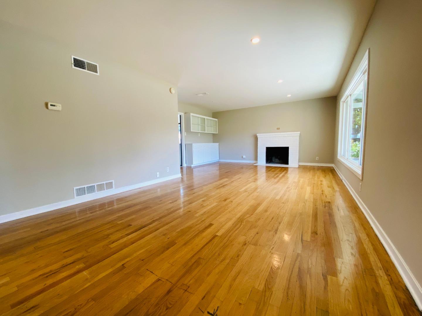 15107 Woodard Road San Jose, CA 95124 - Photo 2 of 20 an empty room with wooden floor and fireplace
