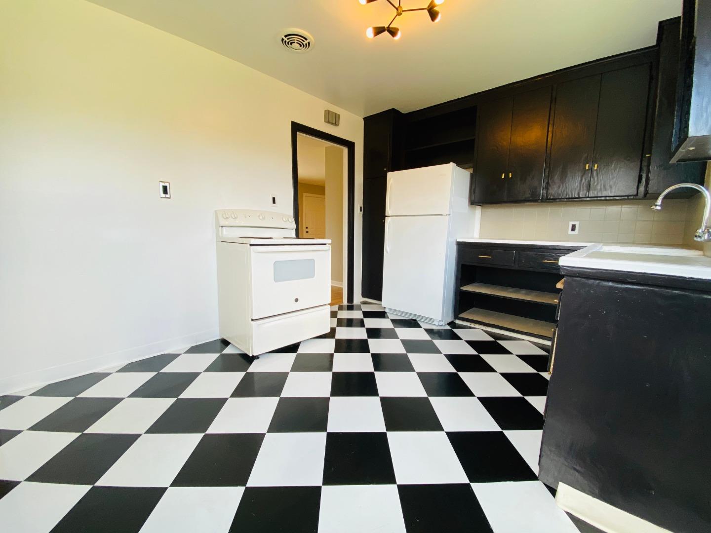 15107 Woodard Road San Jose, CA 95124 - Photo 9 of 20 a kitchen with a checkered floor and white cabinets