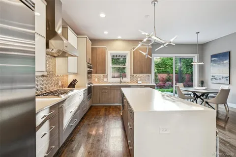 a large white kitchen with a large window and stainless steel appliances