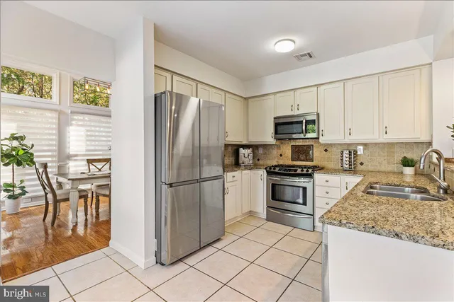 a kitchen with granite countertop a refrigerator and a stove top oven