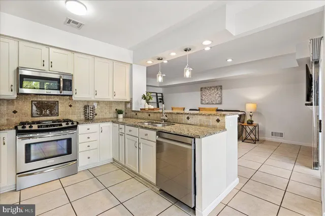 a kitchen with stainless steel appliances granite countertop a stove a sink and a microwave