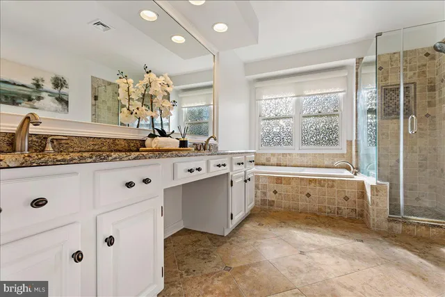 a spacious bathroom with a granite countertop sink a mirror and a bathtub