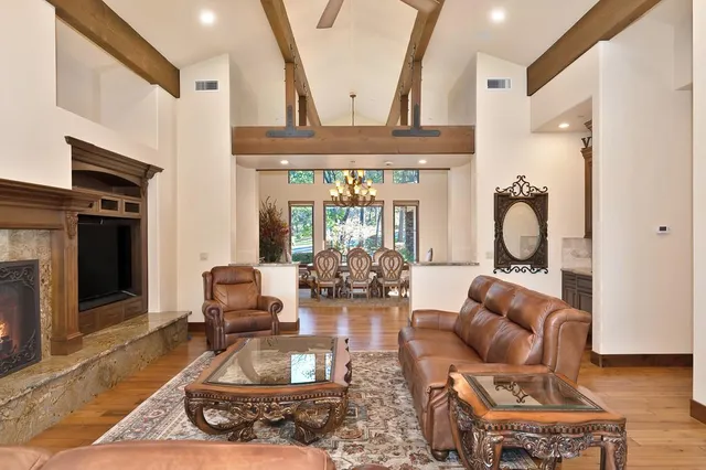 a large living room with stainless steel appliances granite countertop furniture a fireplace a flat screen tv and a large window