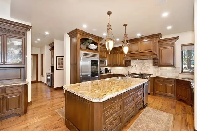 a kitchen with kitchen island granite countertop a stove and a sink