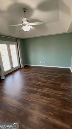 an empty room with wooden floor cabinet and windows