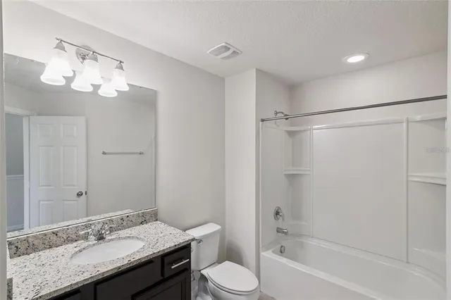 a bathroom with a granite countertop sink a toilet and shower