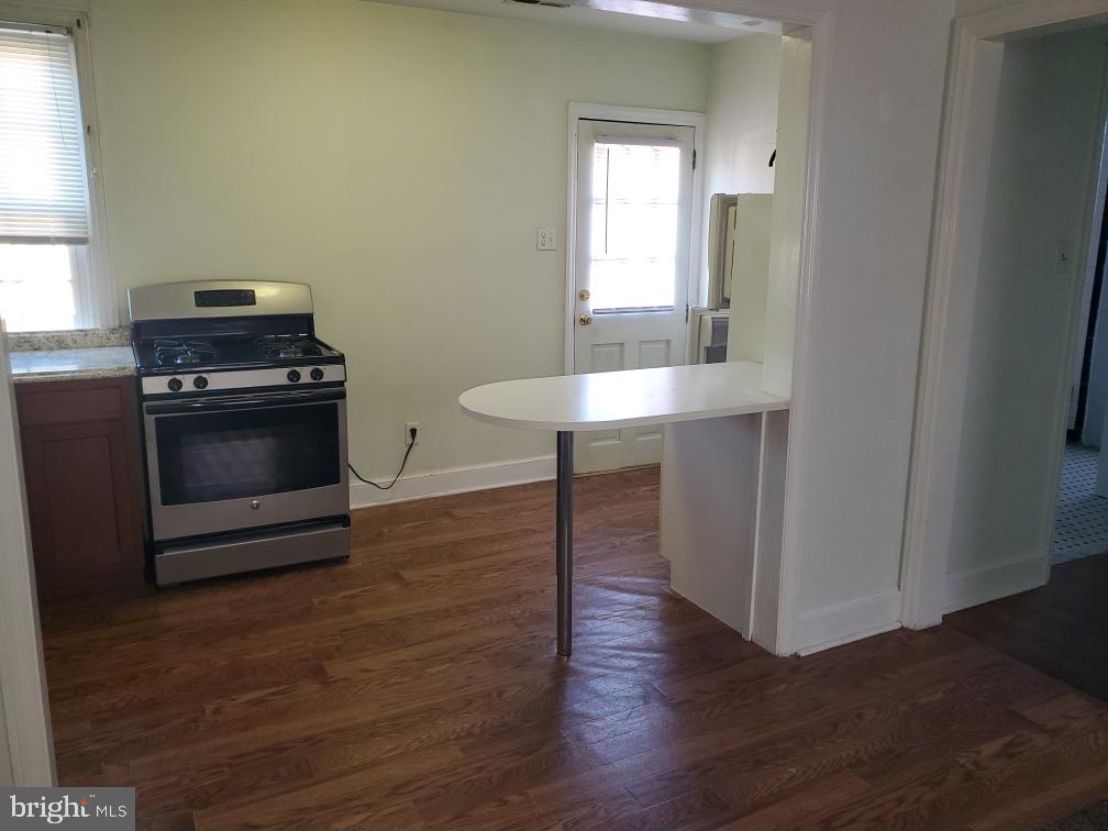 5 Winston Avenue, Unit 1 Wilmington, DE 19804 - Photo 3 of 8 a kitchen with granite countertop a stove and a wooden floor