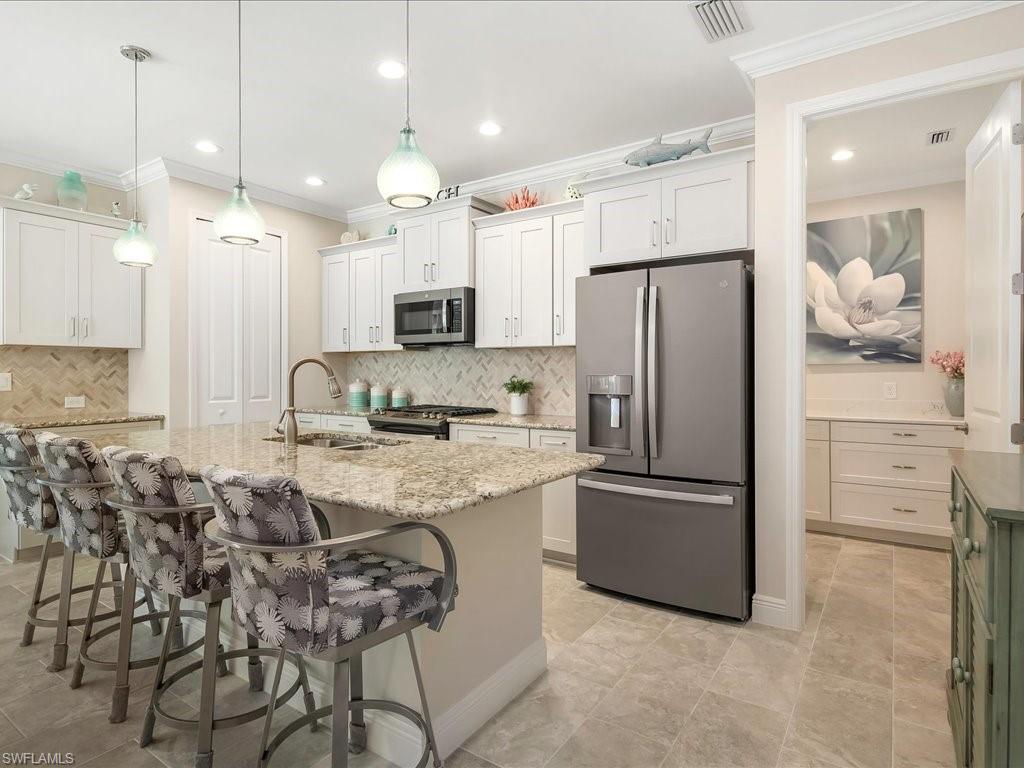 2227 Marquesa Circle Naples, FL 34112 - Photo 9 of 26 a kitchen with kitchen island granite countertop a refrigerator oven a sink a stove and white cabinets