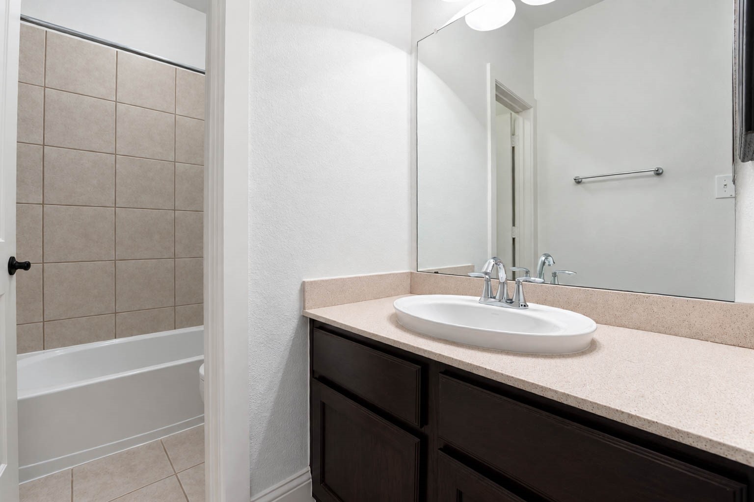 5403 Mesquite Ridge Street Fulshear, TX 77441 - Photo 30 of 42 Family and guests will appreciate this clean, bright full bathroom, which offers a roomy vanity with dark cabinetry and a smooth countertop. A tub and shower combination with a tile surround sits just beyond the door.
