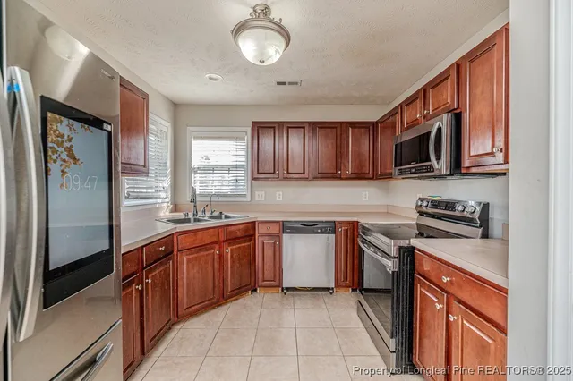 a kitchen with stainless steel appliances granite countertop wooden cabinets a stove top oven a sink and dishwasher