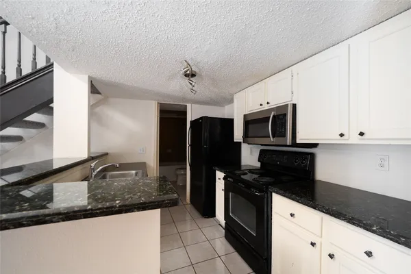 a kitchen with granite countertop a refrigerator and a stove top oven
