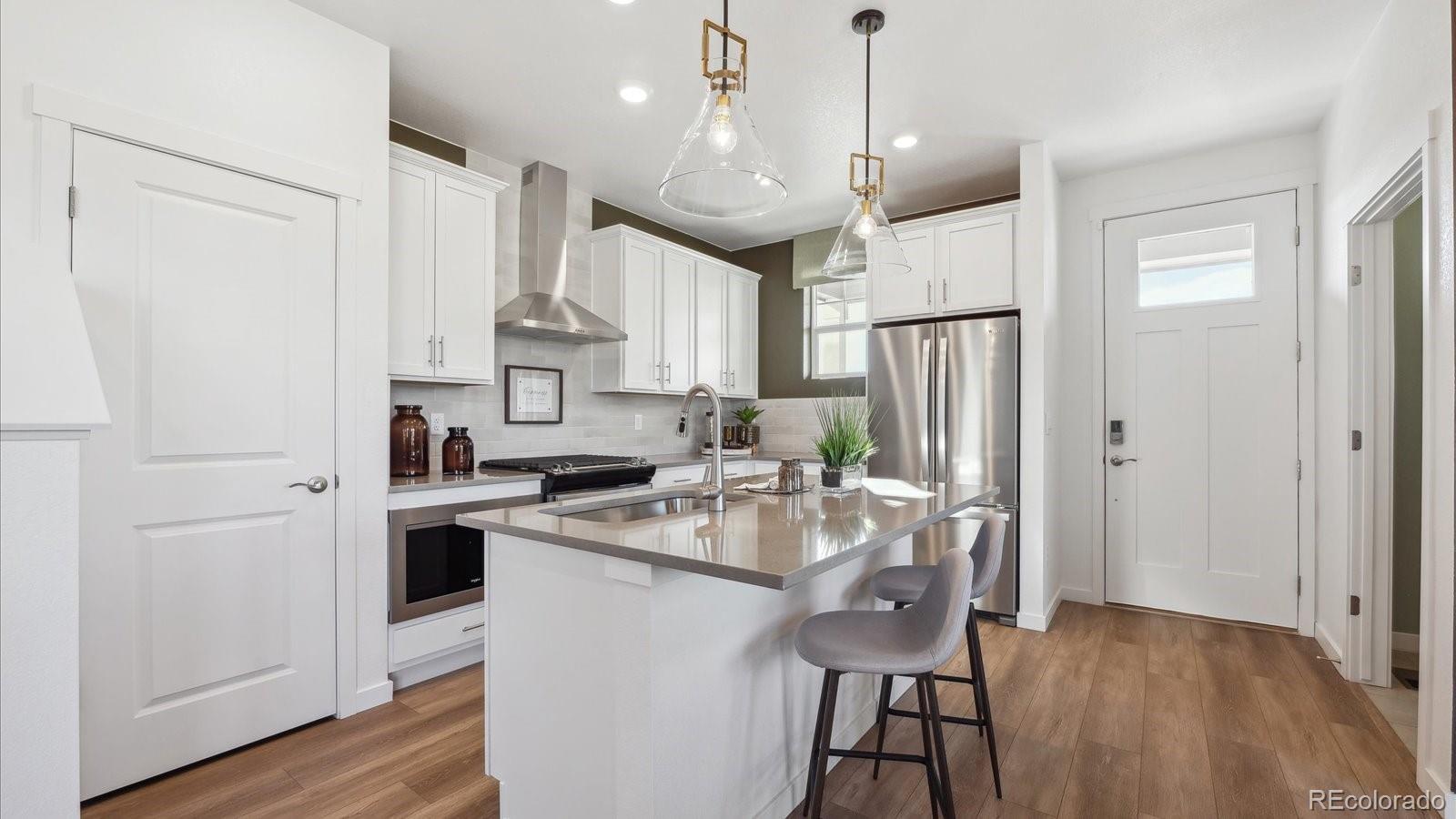 906 Logan Peak Way Berthoud, CO 80513 - Photo 9 of 29 a kitchen with stainless steel appliances granite countertop a refrigerator a sink dishwasher a stove and white cabinets with wooden floor
