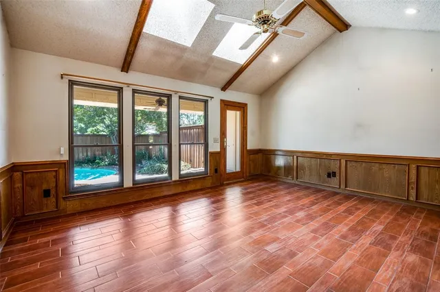 a view of empty room with wooden floor and fan