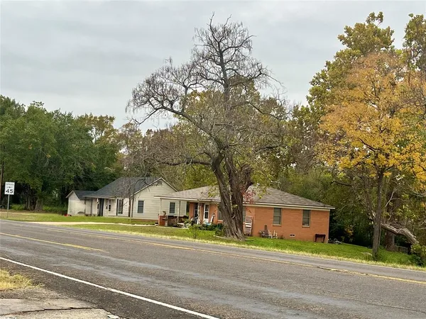 a front view of a house with a garden and trees