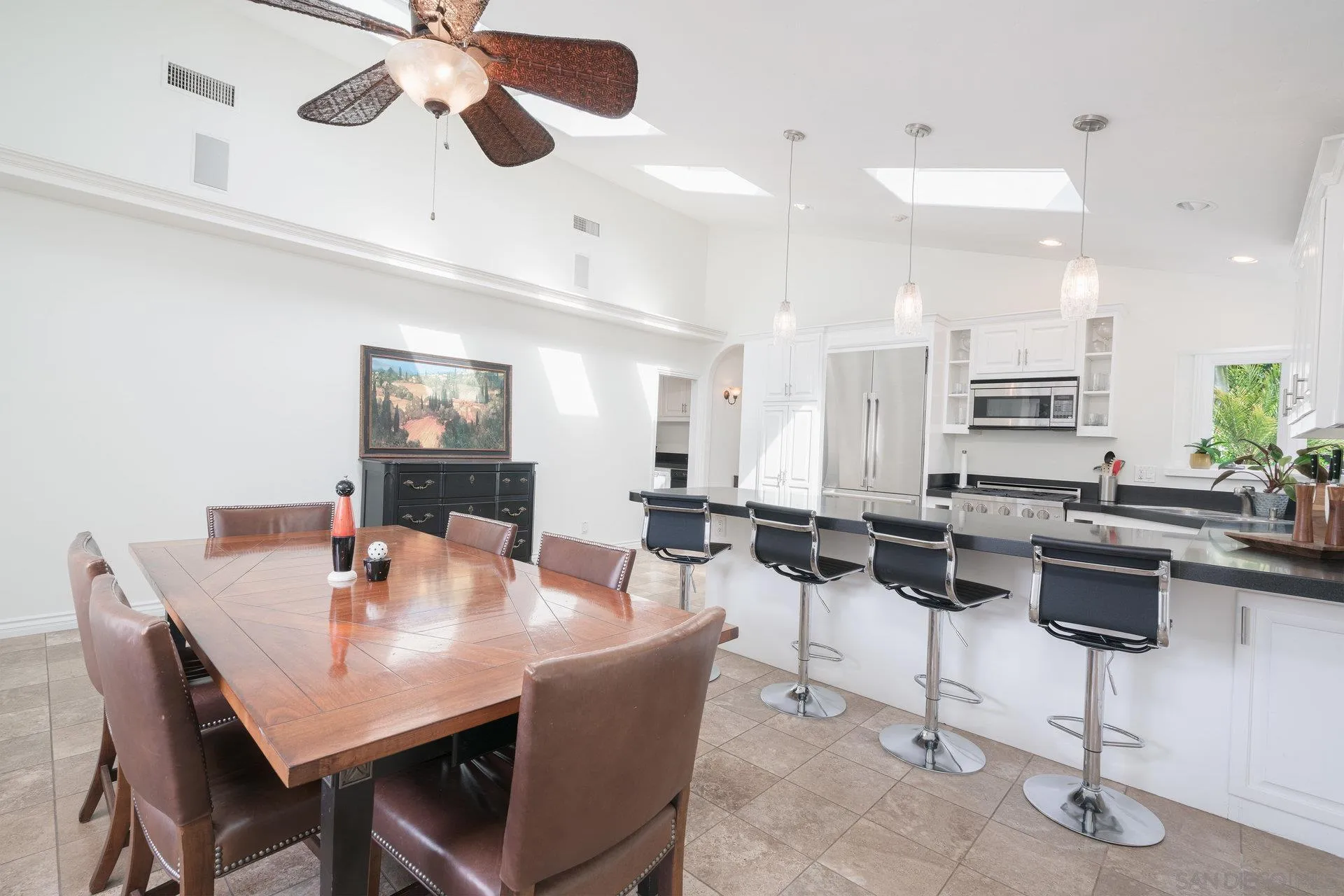 684 Arden Drive Encinitas, CA 92024 - Photo 47 of 59 a dining room with wooden floor a chandelier fan a wooden table and chairs