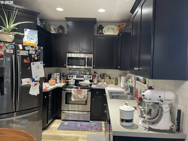 a kitchen with stainless steel appliances granite countertop a sink dishwasher stove and refrigerator with wooden floor