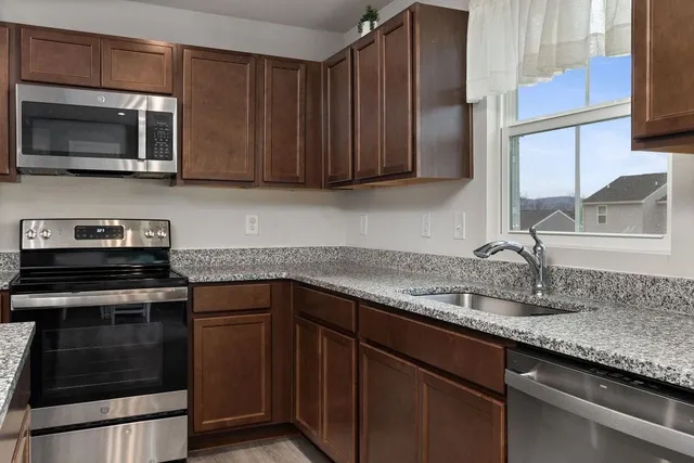 a kitchen with granite countertop wooden cabinets and stainless steel appliances