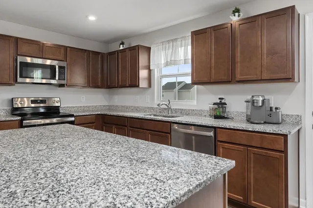 a kitchen with stainless steel appliances granite countertop a sink stove and microwave