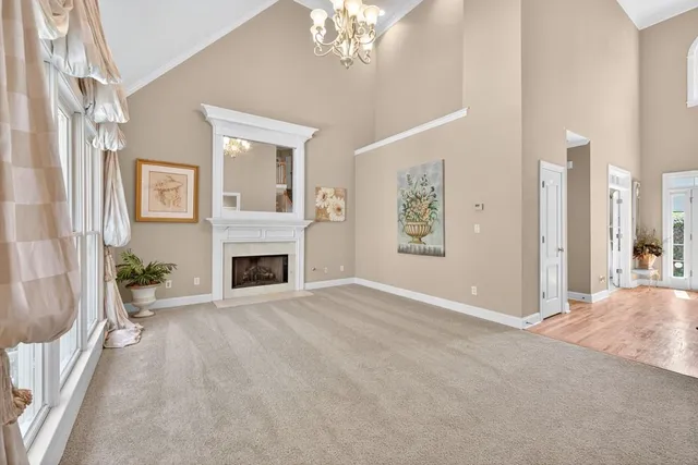 a view of a livingroom with a fireplace a chandelier and windows