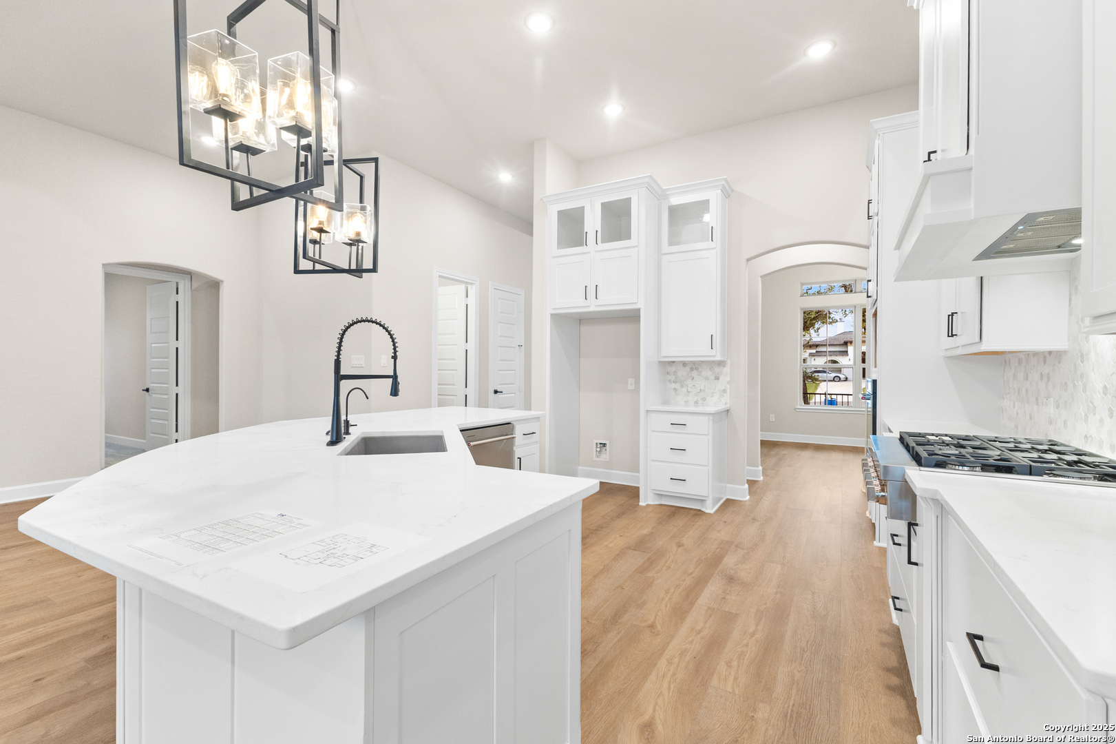 399 James Way Castroville, TX 78009 - Photo 12 of 32 a large kitchen with stainless steel appliances a stove a sink a refrigerator white cabinets and wooden floor