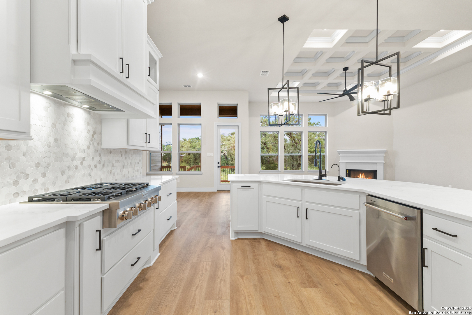 399 James Way Castroville, TX 78009 - Photo 13 of 32 a large kitchen with cabinets a sink dishwasher a stove and a dining table with wooden floor