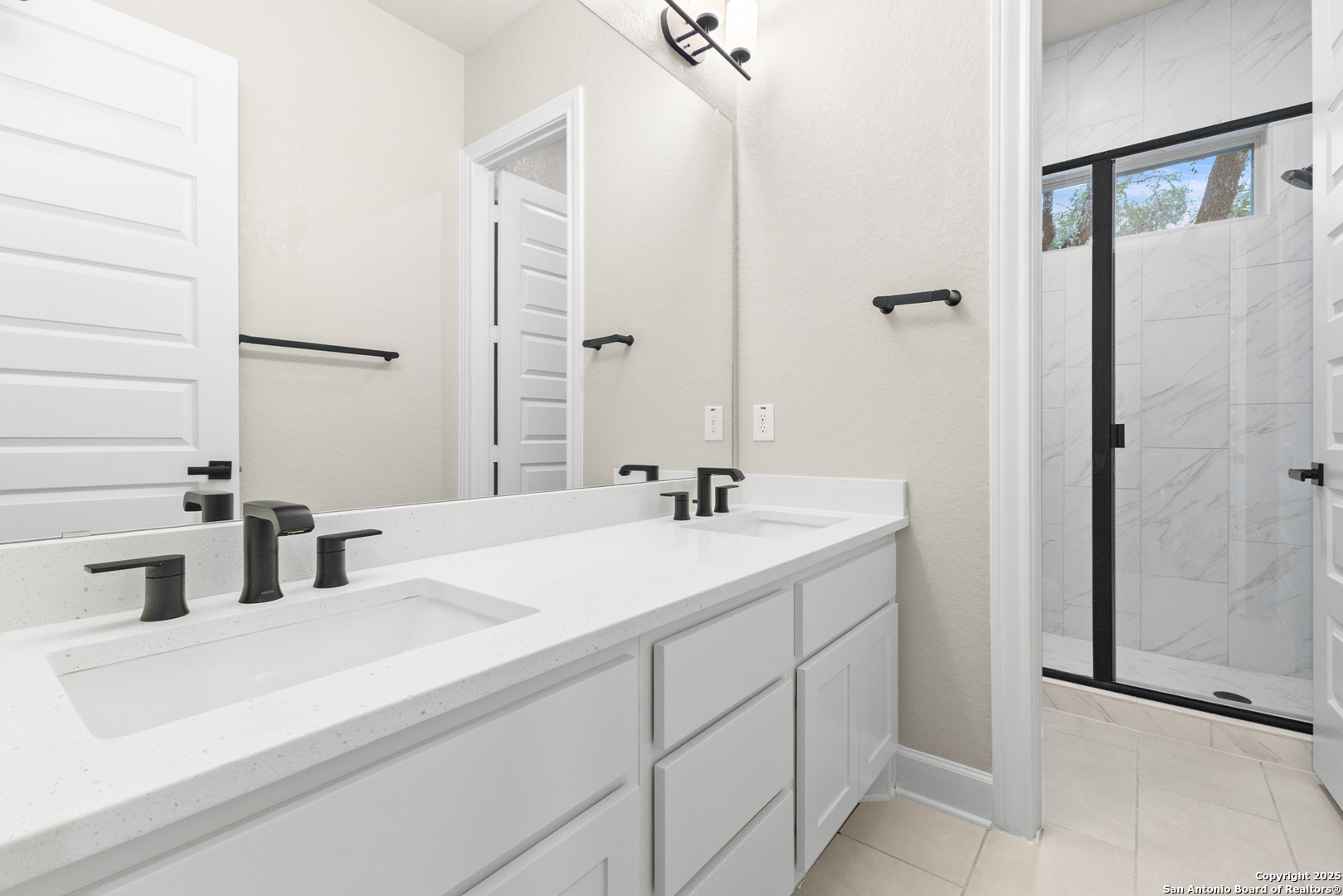 399 James Way Castroville, TX 78009 - Photo 27 of 32 a bathroom with a double vanity sink a mirror and shower