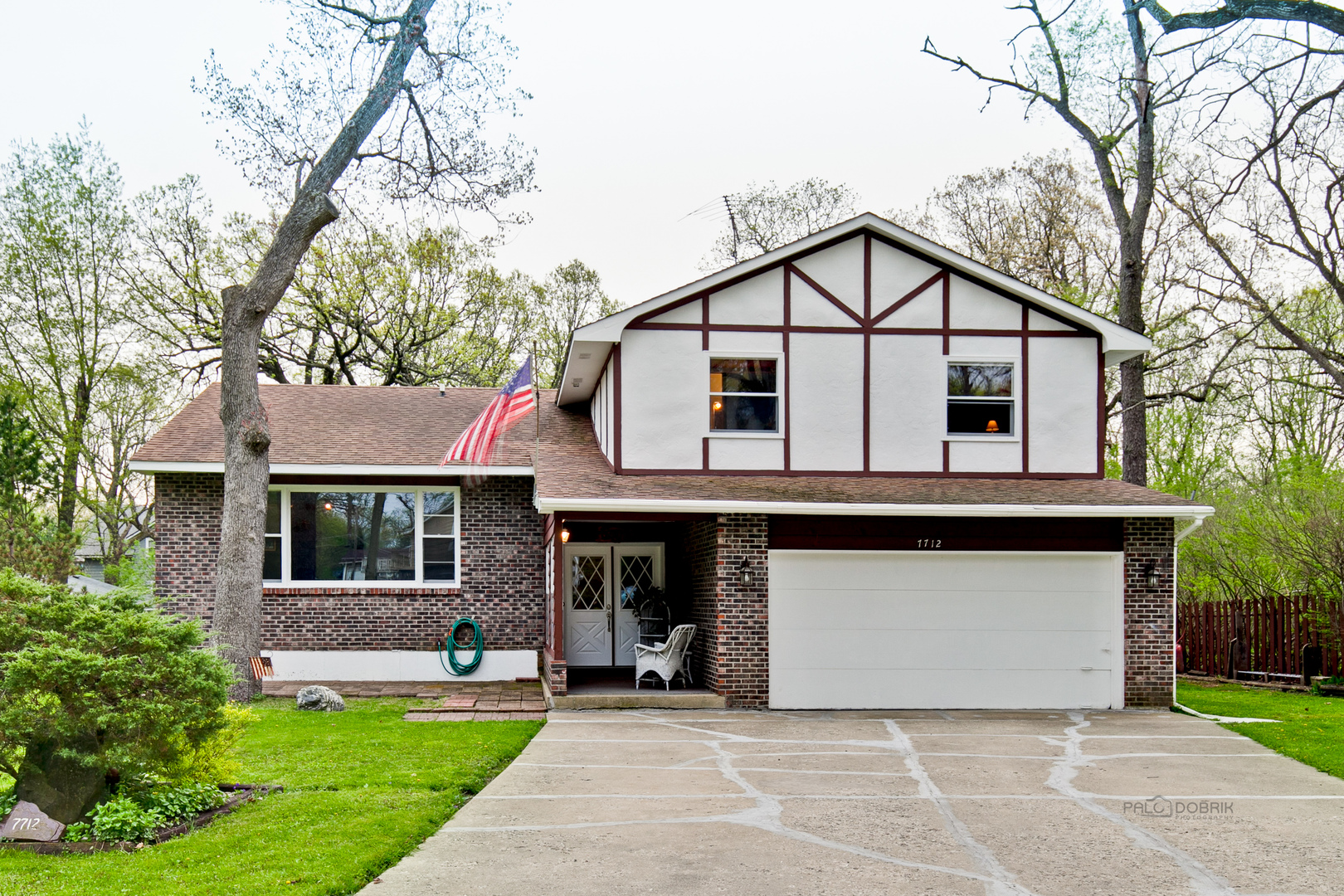 a front view of a house with a garden and trees