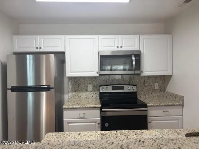 a kitchen with granite countertop a refrigerator stove and microwave