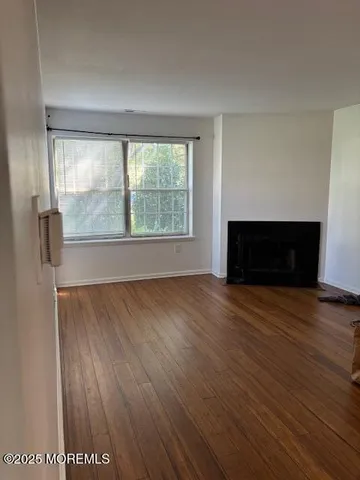 an empty room with wooden floor fireplace and windows