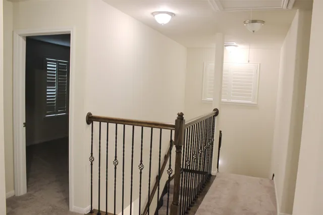 a view of a hallway with wooden floor and a bathroom