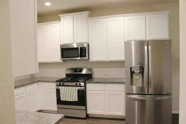 a kitchen with stainless steel appliances white cabinets and a refrigerator
