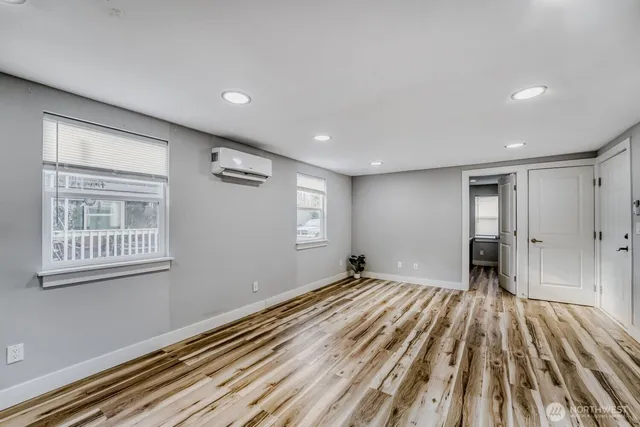 a view of an empty room with wooden floor and a window